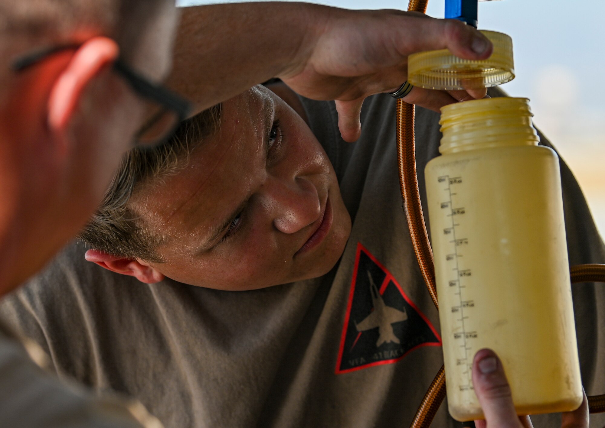 Sailors work underneath aircraft.