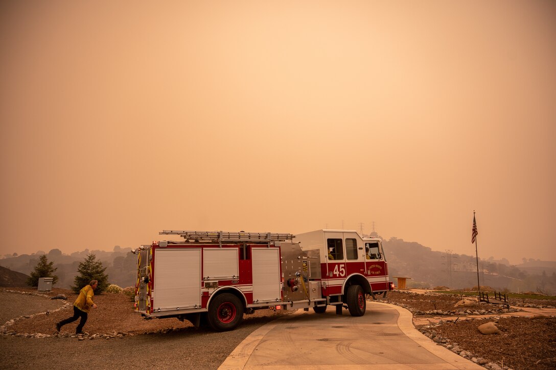 A firefighter walks behind a firetruck.