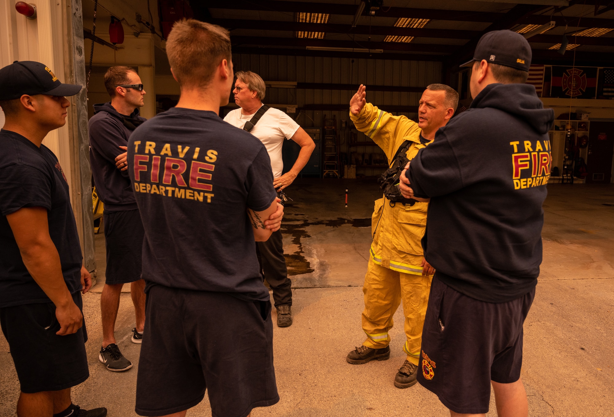 Firefighters standing around listening to a chief brief information about the fire.