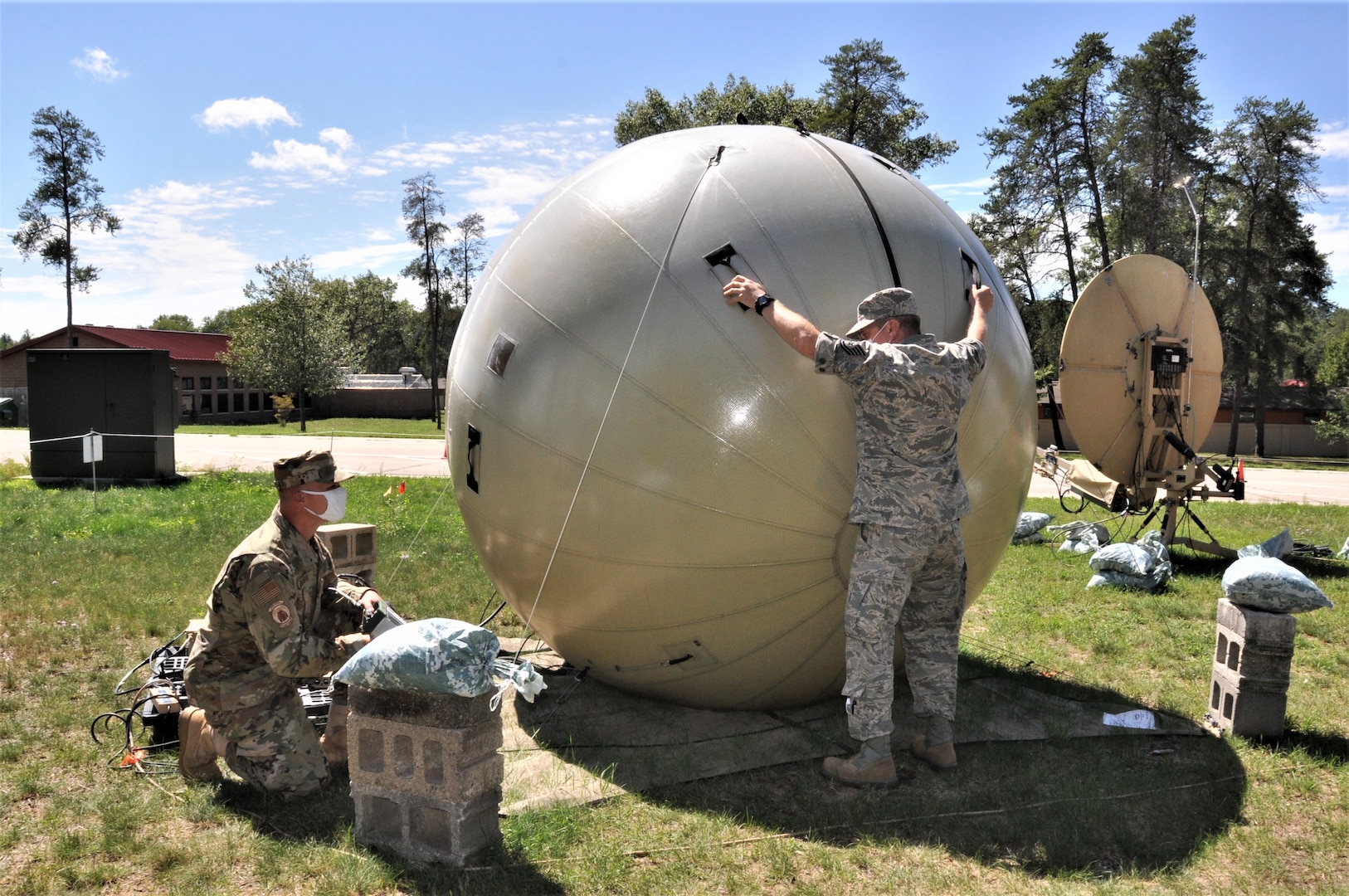 Airmen adjust a communications satellite system.