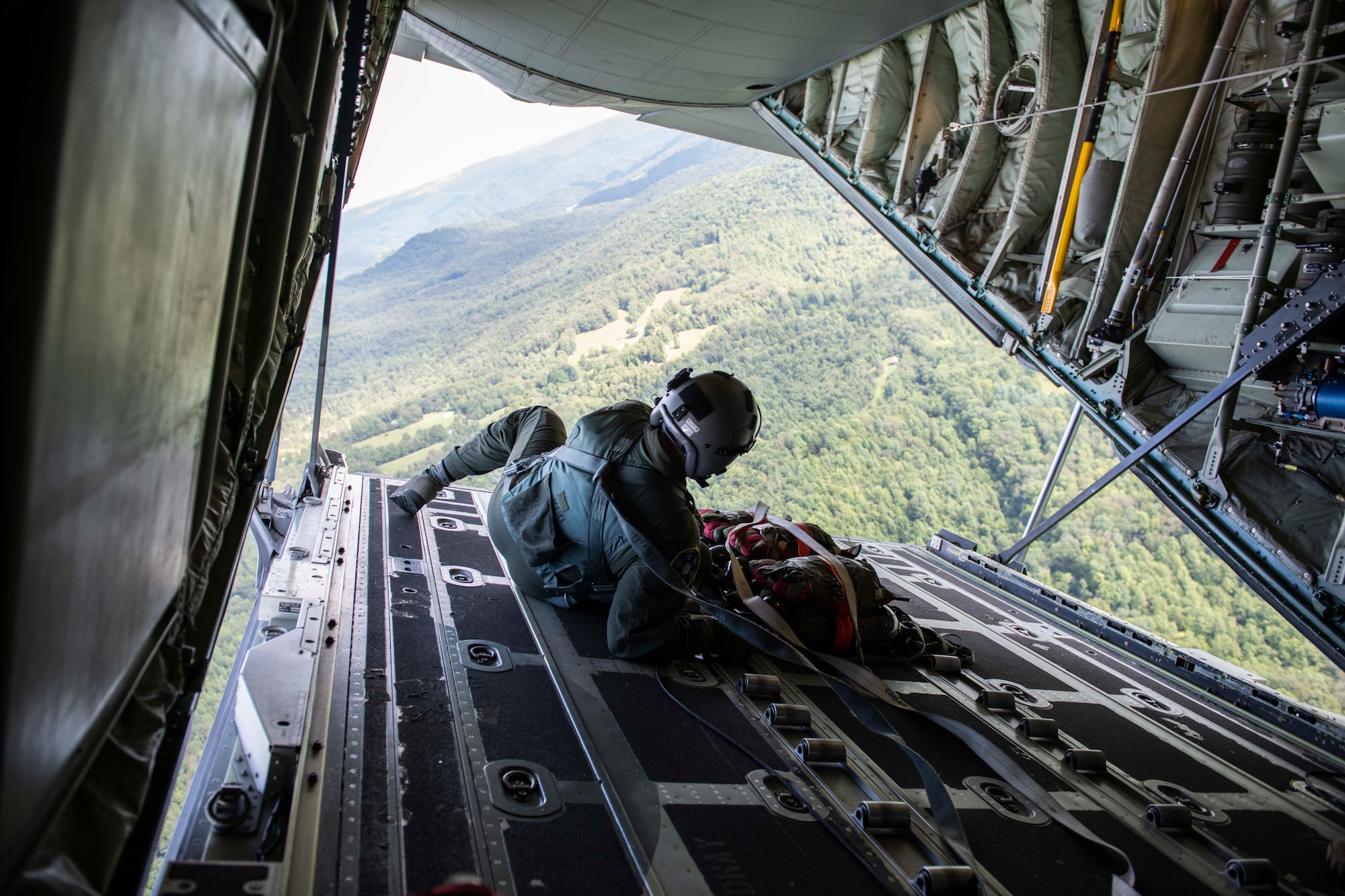 Air Force Reserve loadmaster prepares to launch cargo out of the ramp of a C-130J Super Hercules near Charleston, W. Va., Aug. 23, 2020. The training event tested aircrew on their tactical combat airlift capabilities such as cargo airdrop, formation flights, and personnel delivery in a contested environment. There were a total of eight aircraft from six units supporting the training effort, enabling strategic depth and readiness for the force. (U.S. Air Force Reserve photo by Senior Airman Nathan Byrnes)