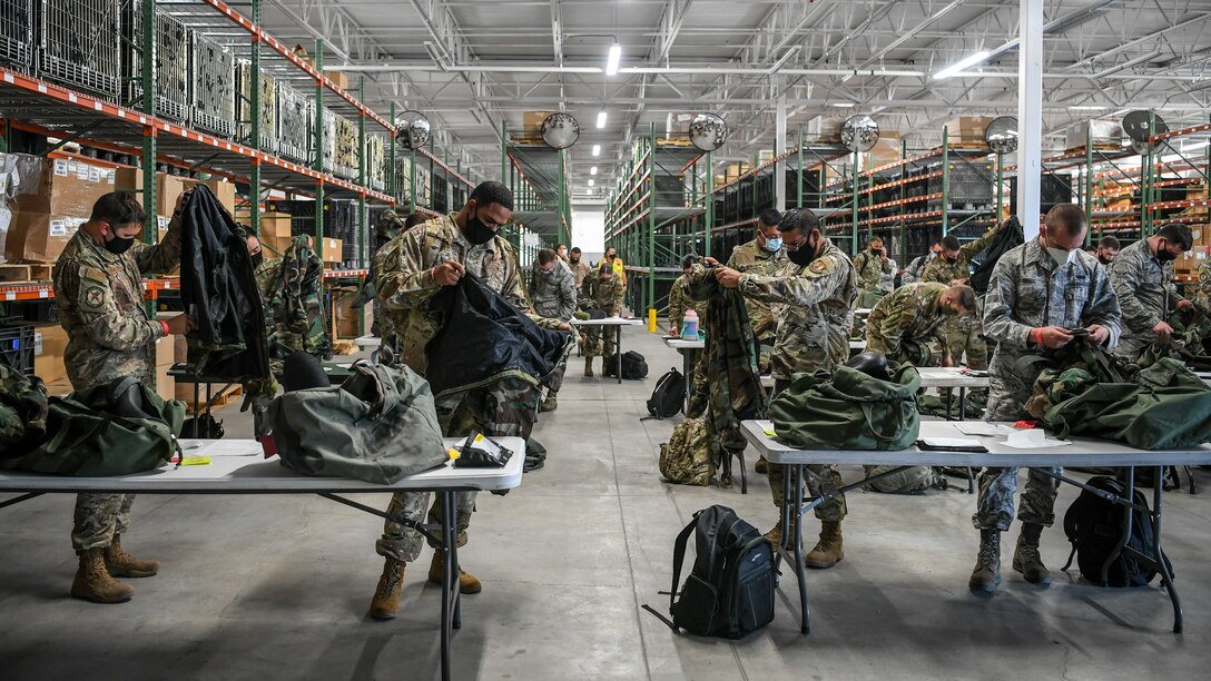 Dozens of Airmen check their mobility gear on tables.