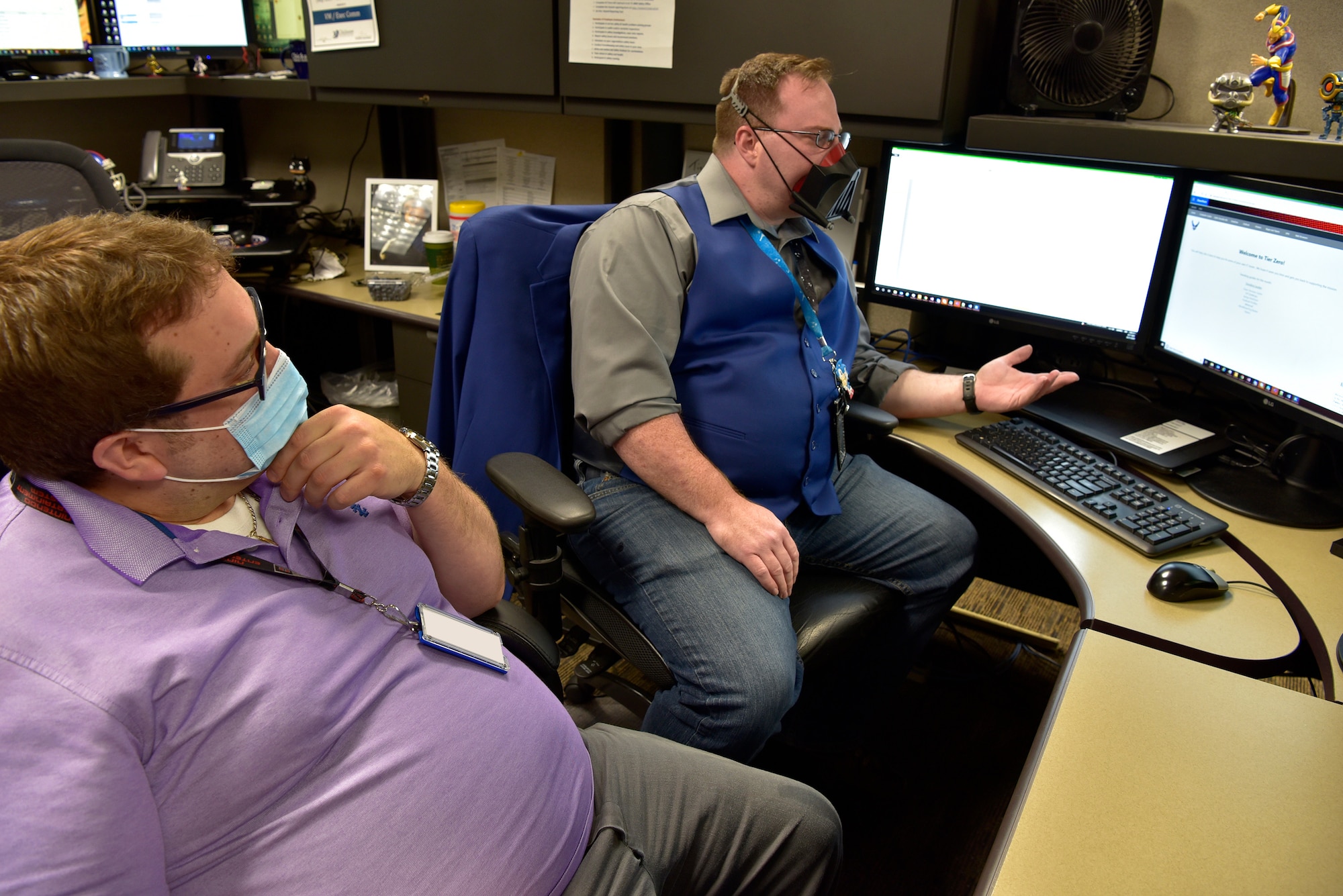 Two men talking in front of computer