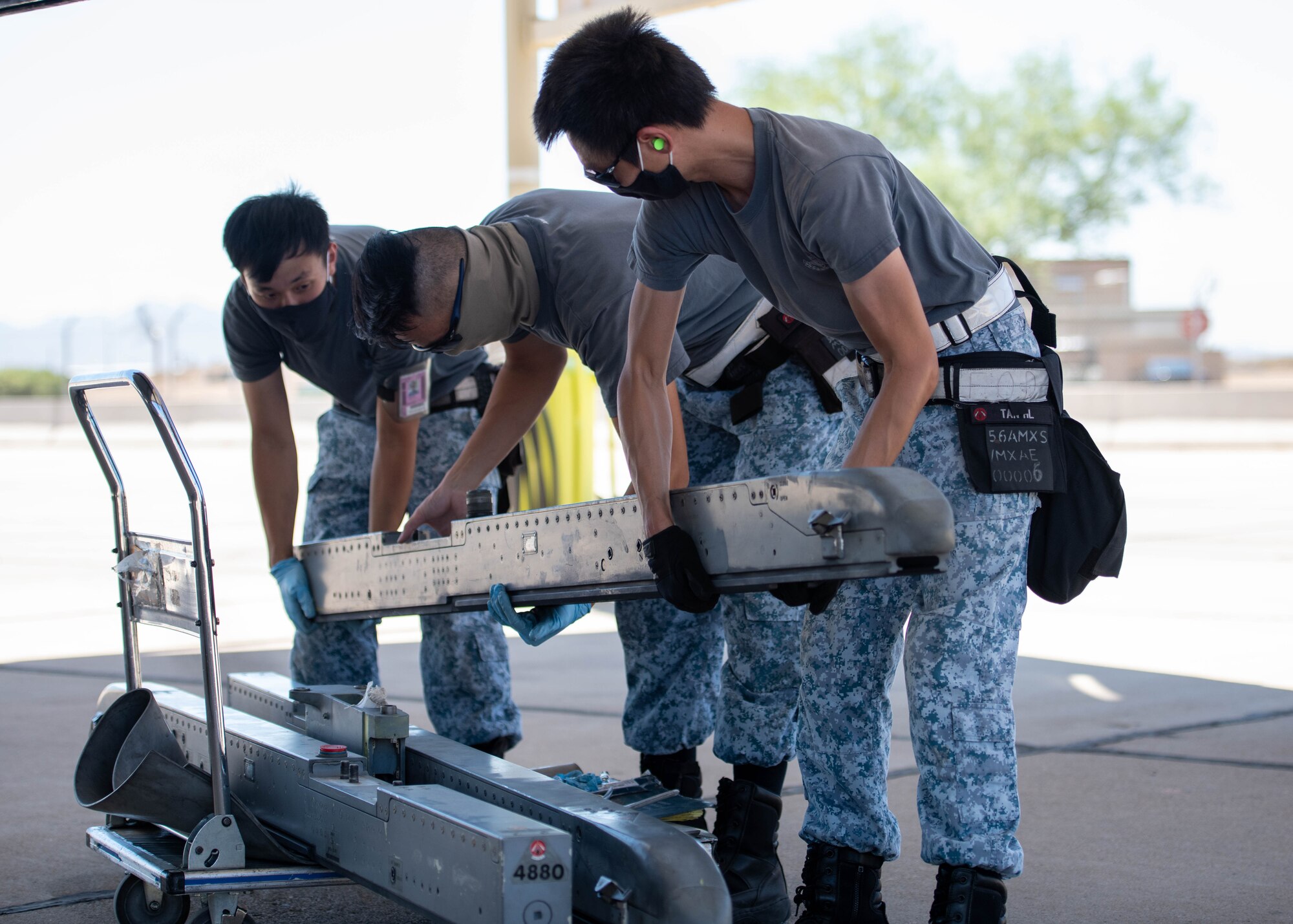 From left to right, Republic of Singapore Air Force Military Expert One Staff Sgt. Chan Jun Heng Andy, Military Expert Two Master Sgt. Teo Choh Hwai, and ME2 Master Sgt. Tan Hock Leng, 425th Fighter Squadron maintainers, prepare to install an LAU-129 missile onto an F-16D Fighting Falcon Aug. 5, 2020, at Luke Air Force Base, Ariz.