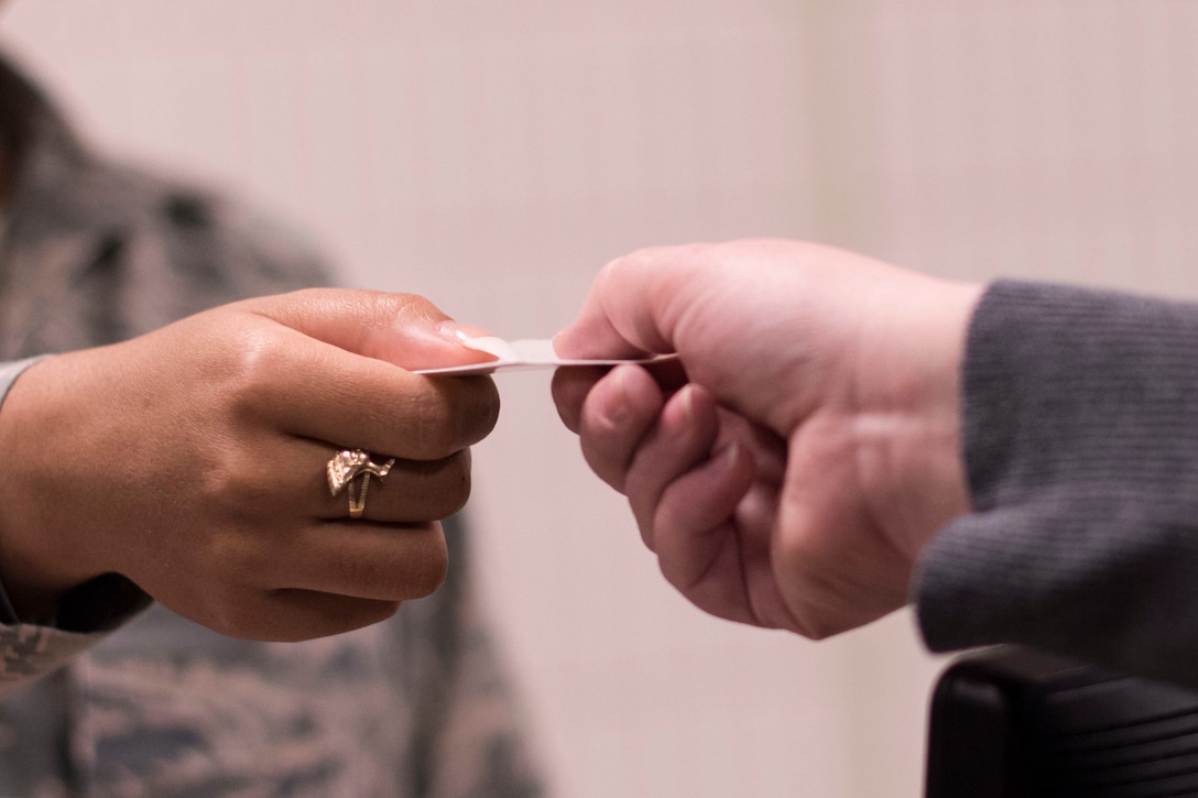 An airman hands an ID card to a family member.