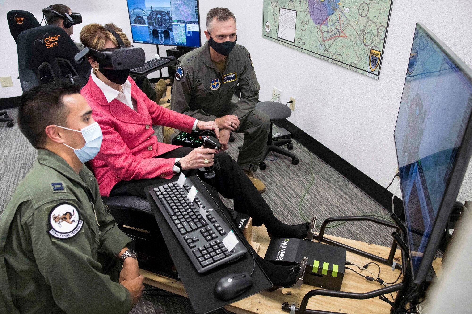 Secretary of the Air Force Barbara Barrett uses a virtual reality flight simulator as U.S. Air Force Capt. Orion Kellogg (left) and Maj. Gen. Craig Wills, 19th Air Force commander (right), look on  during her visit to Undergraduate Pilot Training 2.5 Aug. 20, 2020, at Joint Base San Antonio-Randolph, Texas. Barrett, along with Chief of Staff of the Air Force Charles Q. Brown Jr., and Chief Master Sgt. of the Air Force JoAnne Bass toured Air Education and Training Commands UPT 2.5  program, which scales lessons learned from Pilot Training Next as part of their first joint visit.