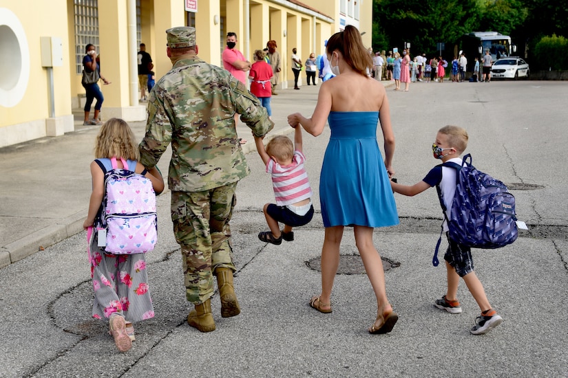 Three children and their parents hold hands as they walk together.