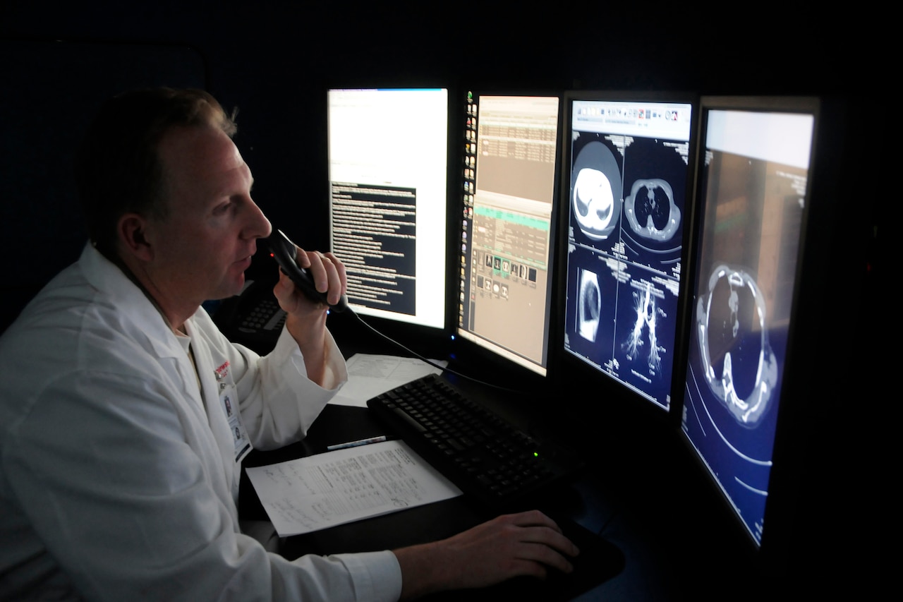 A medical professional looks at medical scans on a computer screen.