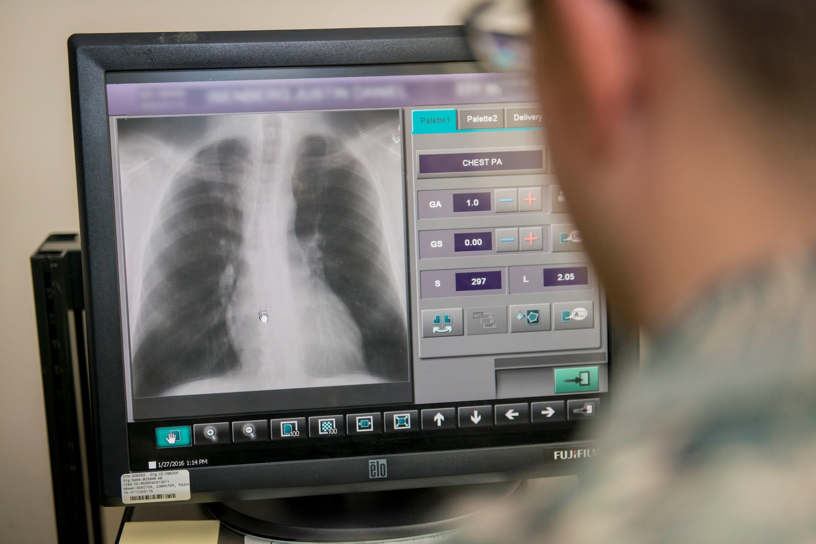 A person in a military uniform looks at an X-ray on a computer screen.