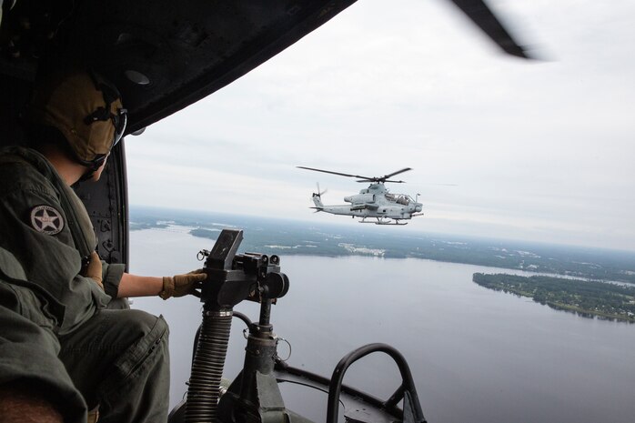 Cpl. Bryce Hawkins, an aerial observer with Marine Light Attack Helicopter Squadron 269, flies in a UH-1Y Huey next to an AH-1Z Viper during Exercise Deep Water 2020 over Marine Corps Air Station New River, North Carolina, July 29, 2020. The purpose of the exercise is to increase 2nd Marine Aircraft Wing's interoperability and readiness on a scale that simulates peer-level threats. (U.S Marine Corps Photo by Cpl. Juan C. Dominguez)