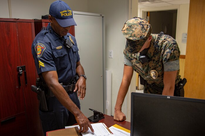 McGill Howard, left, a civilian police officer, briefs U.S. Marine Corps Lance Cpl. Samuel Spearman, right, a military police officer about the Field Training Officer program at the Provost Marshal Office on Marine Corps Air Station New River, North Carolina, July 31, 2020. MCAS New River has introduced the Field Training Officer program in order to ensure that military police officers are trained to be proficient and skillful at their duties. Both Howard and Spearman are police officers with Headquarters and Support Battalion, Marine Corps Installations East-Marine Corps Base Camp Lejeune. (U.S. Marine Corps Photo by Lance Cpl. Isaiah Gomez)