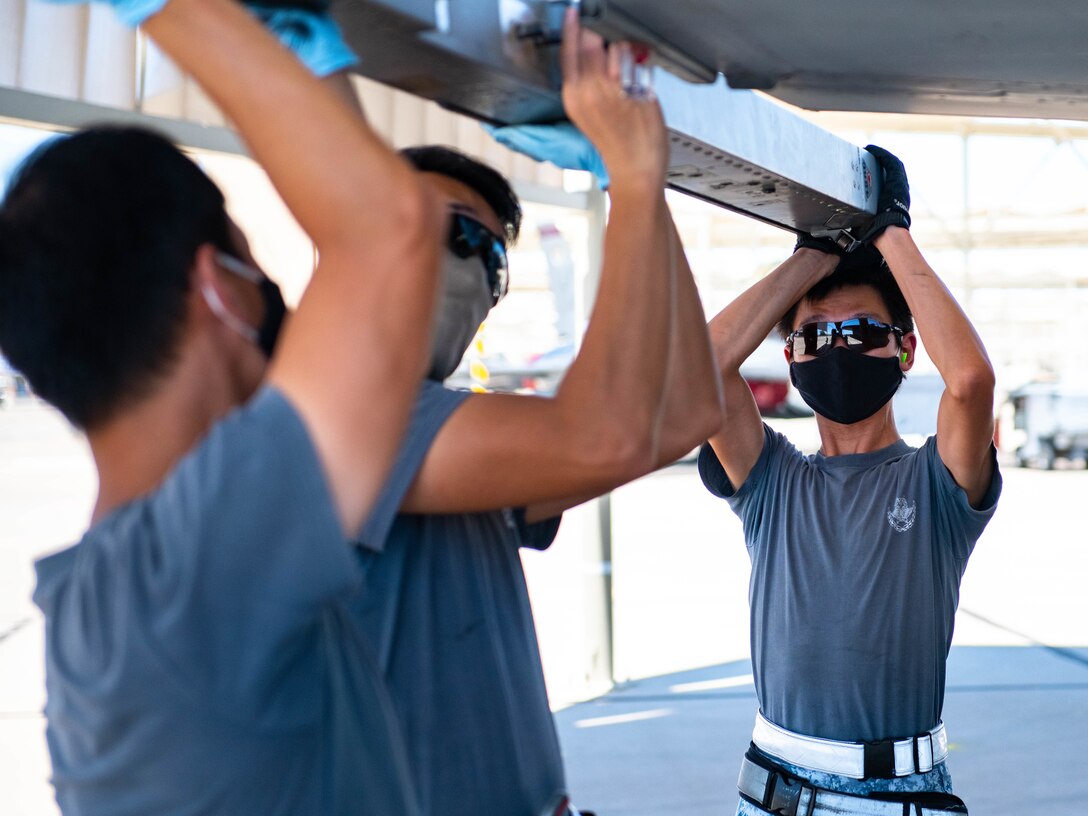 From left to right, Republic of Singapore Air Force Military Expert One Staff Sgt. Chan Jun Heng Andy, Military Expert Two Master Sgt. Teo Choh Hwai and ME2 Master Sgt. Tan Hock Leng, 425th Fighter Squadron maintainers, install a missile on an F-16D Fighting Falcon Aug. 5, 2020, at Luke Air Force Base, Ariz.