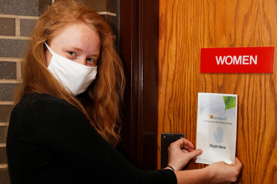 An engineer applies a NanoSeptic protective sheet to a door.