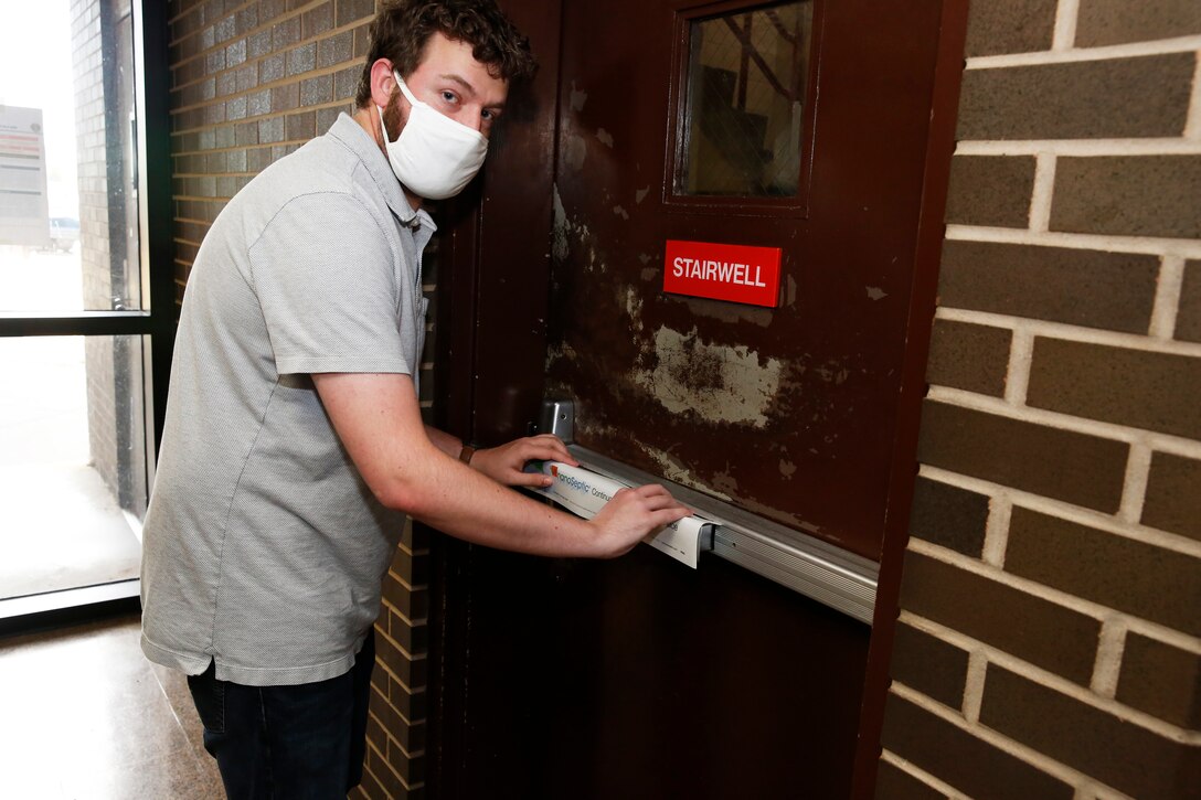 An engineer applies a NanoSeptic protective sheet to a door.