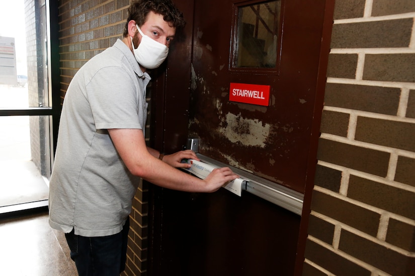 An engineer applies a NanoSeptic protective sheet to a door.