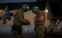 Sailors stand on the flight line.