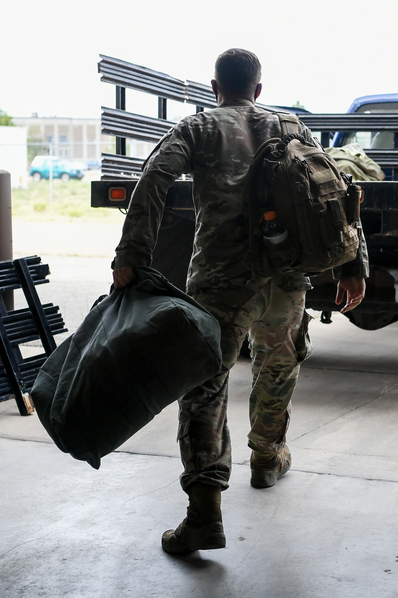 An Airman throws his deployment bag into the back of a flatbed truck.