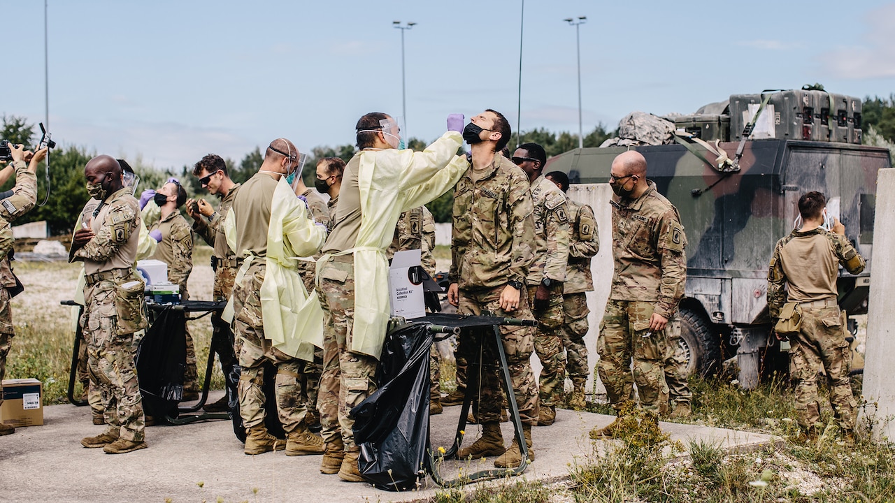 Army medics in protective gear swab test soldiers for COVID-19.