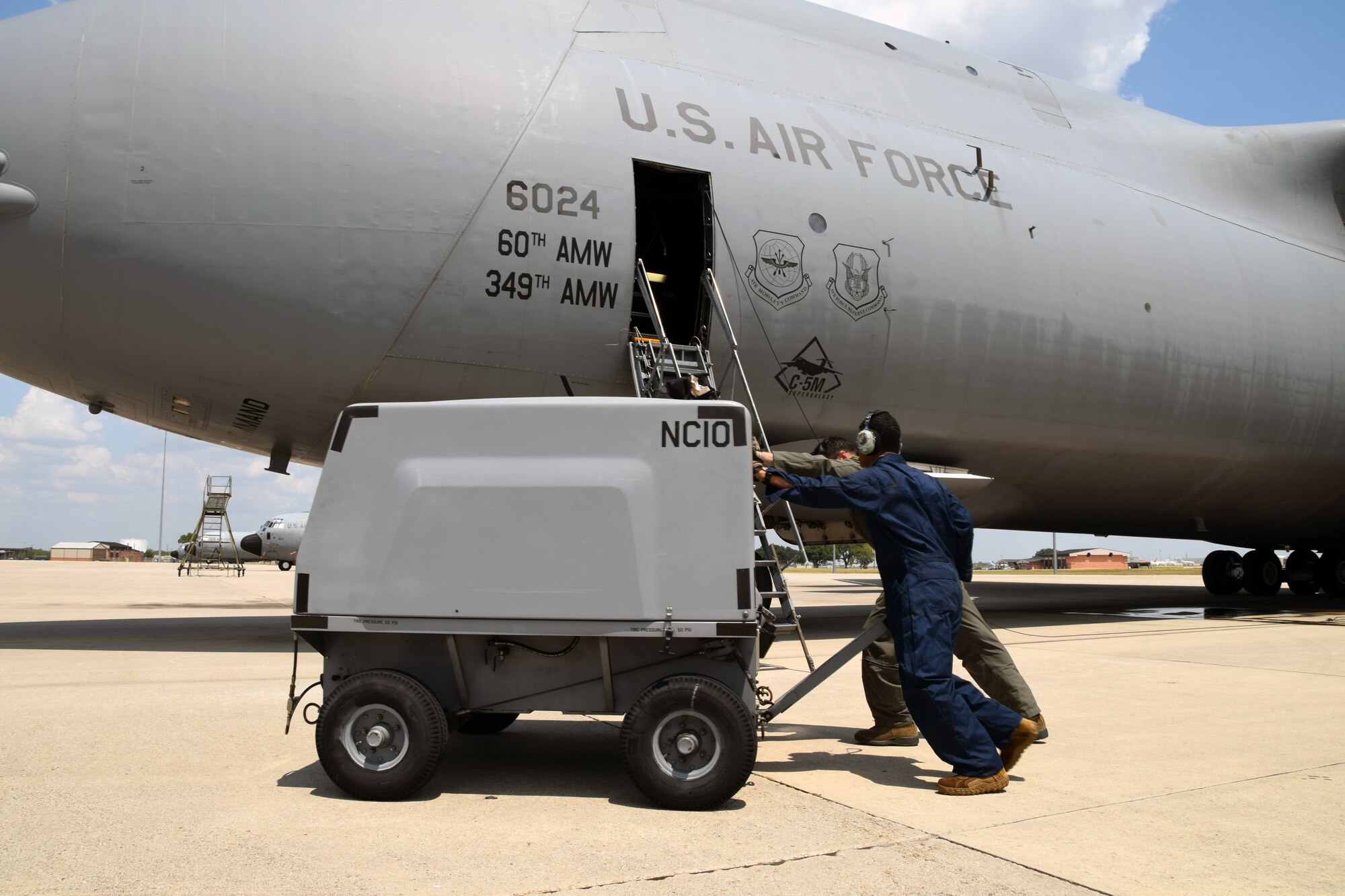 Staff Sgt. Michael Hailemaskel and Senior Airman Glenn C. Bovino II, both with the 60th Aircraft Maintenance Squadron at Travis Air Force Base, California, move an aircraft ground support cart so the C-5M Super Galaxy can depart the airfield Aug. 24, 2020 at Joint Base San Antonio-Lackland, Texas.