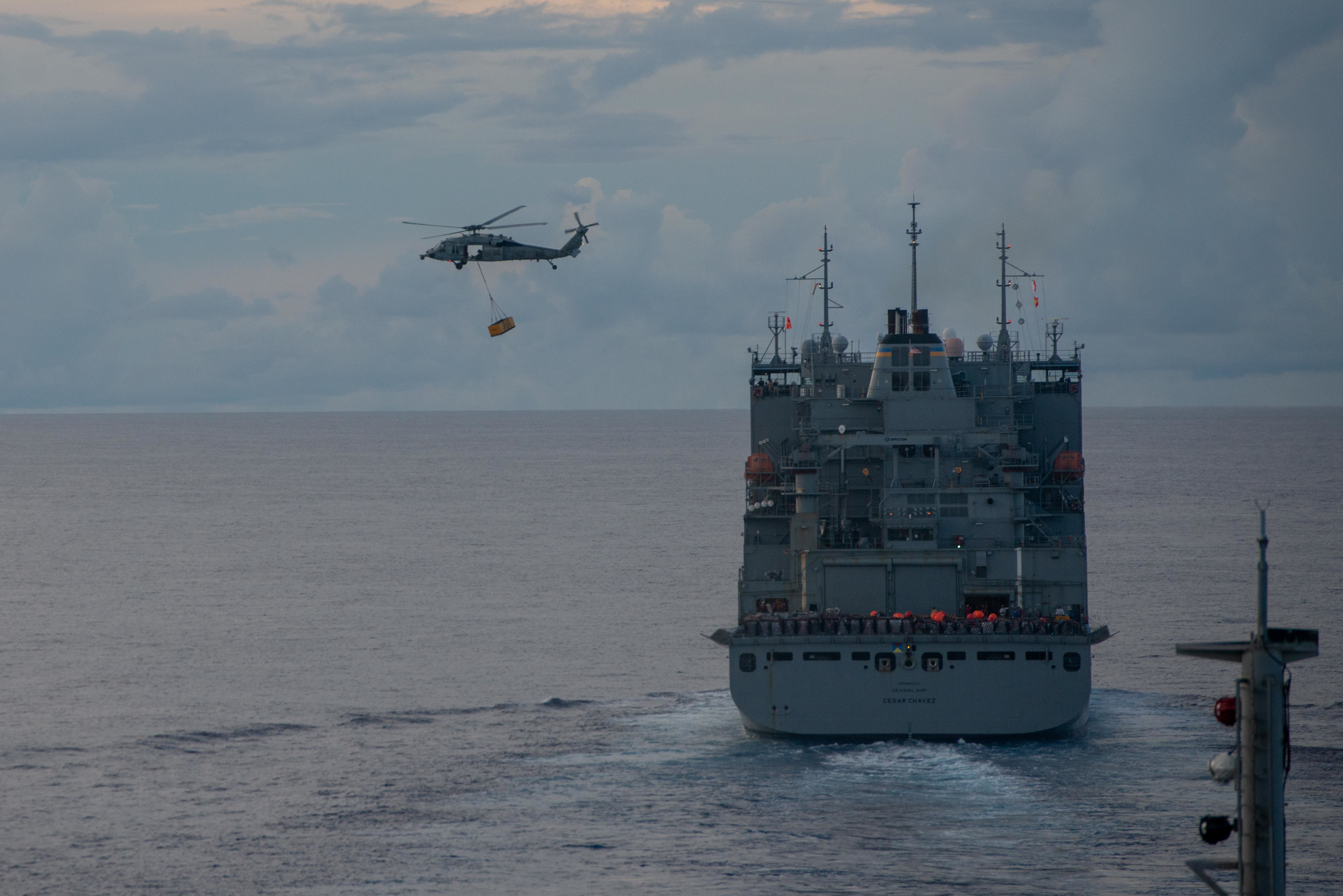 An MH-60S Sea Hawk helicopter attached to the Golden Falcons of Helicopter Sea Combat Squadron (HSC) 12 transports cargo from the dry cargo and ammunition ship USNS Cesar Chavez (T-AKE 14) to the flight deck of the Navy’s only forward-deployed aircraft carrier USS Ronald Reagan (CVN 76) during a replenishment-at-sea.