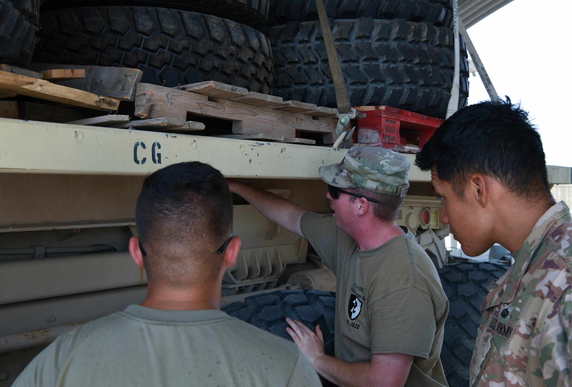 Army Specialist David Chaffin, instructor for the 133rd Battalion, goes over parts of the M1075 Palletized Load System as Specialist Jose Arellano (right) and Air Force Senior Airman Bradley Dabolos, 380th Expeditionary Logistics Readiness Squadron ground transportation apprentice, look on, July 22, 2020 at Al Dhafra Air Base, United Arab Emirates.
