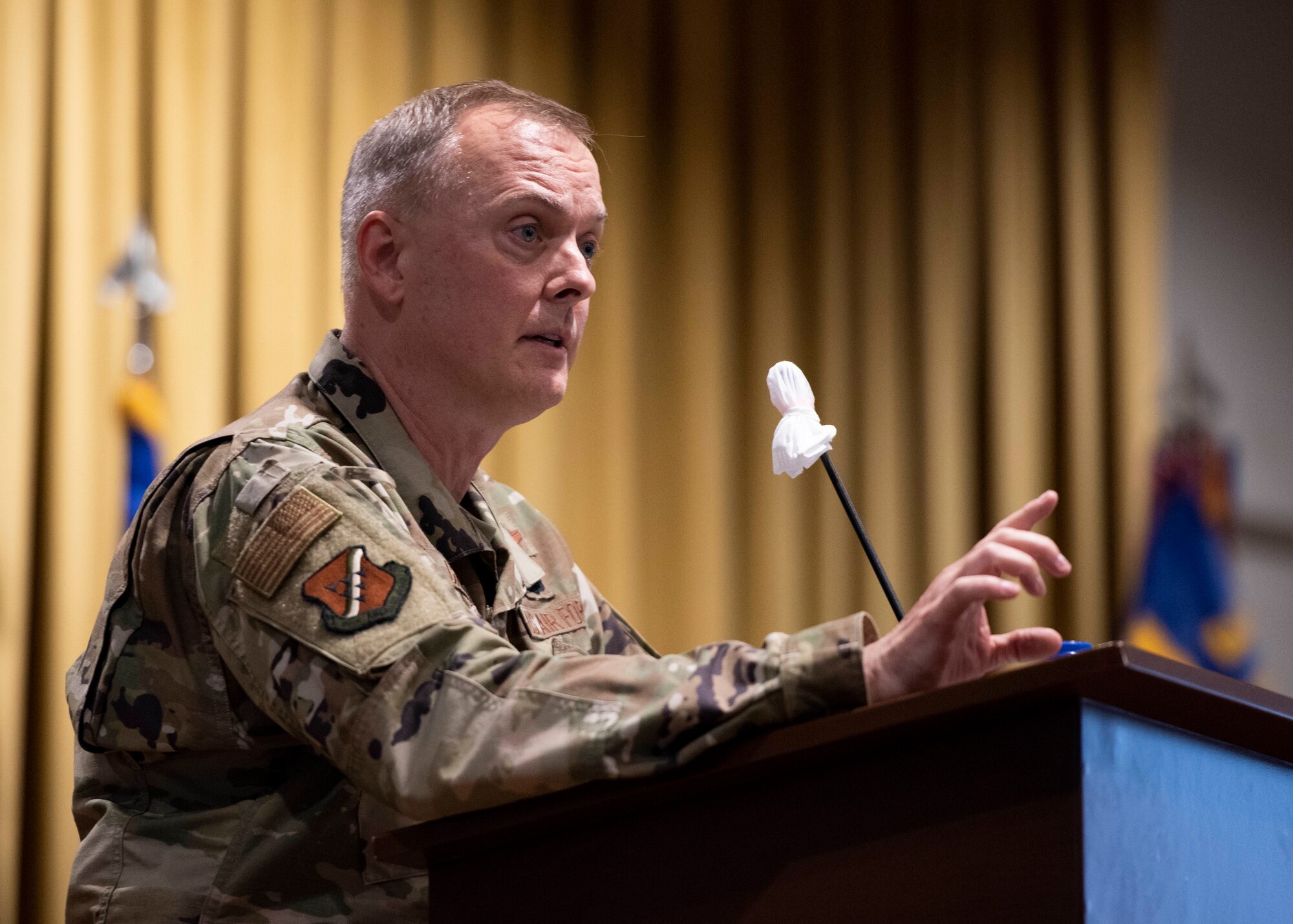 Col. John Creel, 39th Air Base Wing commander, speaks from a stage podium to Airmen in-person and online during a commander’s call at Incirlik Air Base, Turkey, Aug. 25, 2020