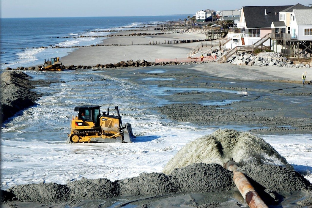 Bulldozer pushes sand from the ocean to the shore.