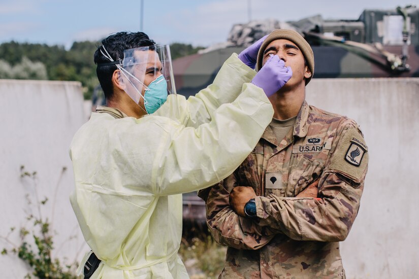 An army medic in full protective gear tests a soldiers for COVID-19.