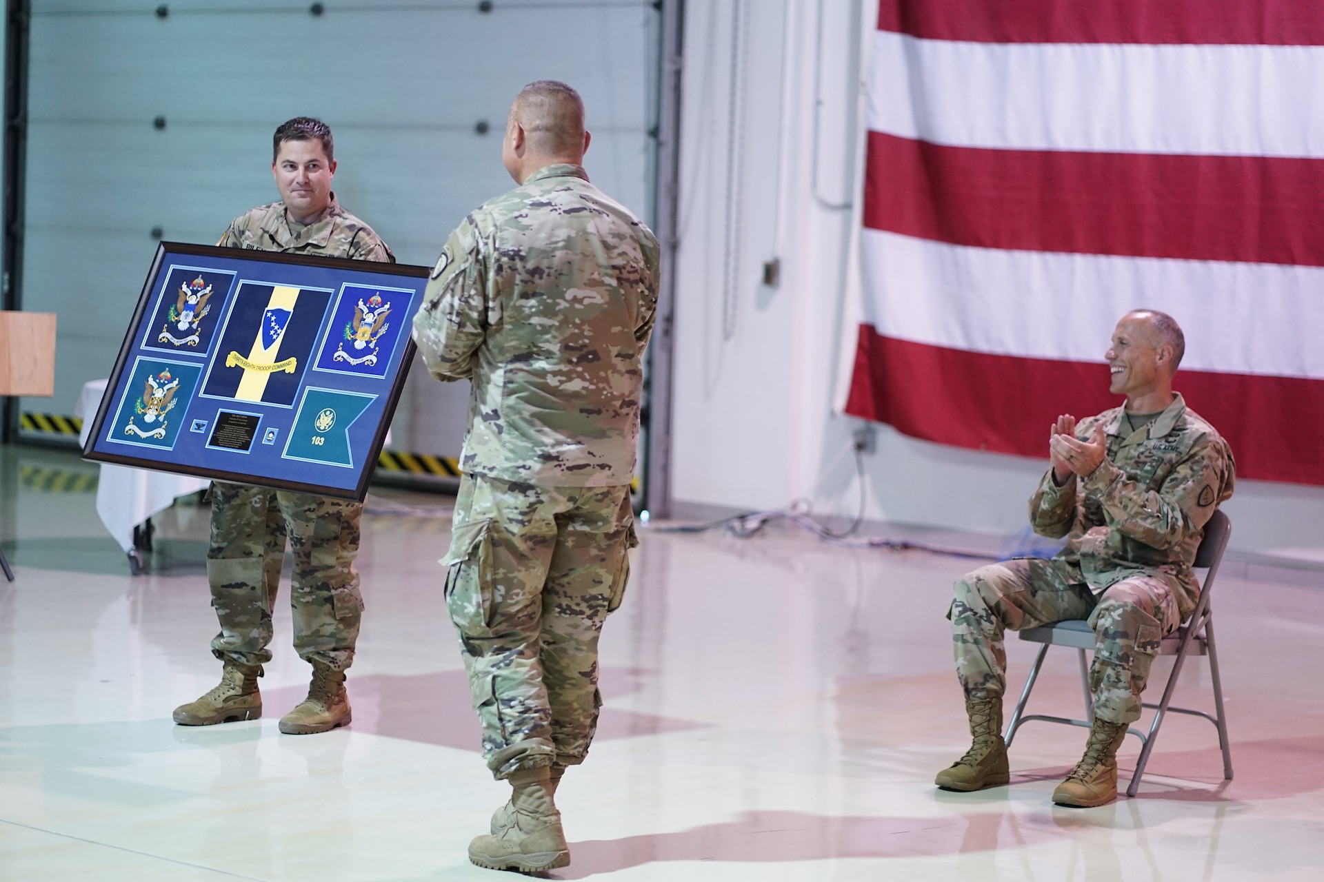 Alaska Army National Guard Maj. Michael Riley, 38th Troop Command adjutant, presents Col. Joel Gilbert, former 38th TC commander, with a gift during an Aug. 2, 2020, change-of-command ceremony at Joint Base Elmendorf-Richardson. Lt. Col. Tim Brower (right) succeeded Gilbert during the ceremony. (U.S. Army National Guard photo by Capt. David Bedard/Released)