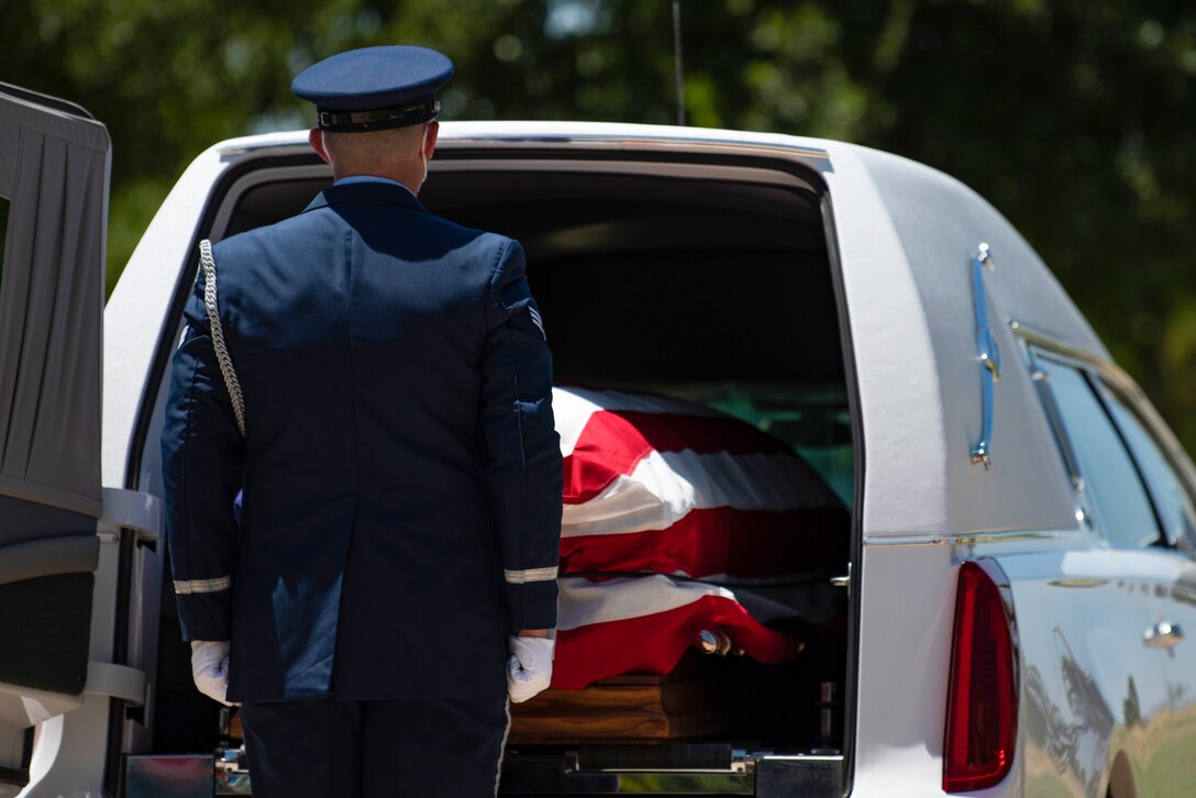 Senior Airman Kyle McLaughlin, 7th Force Support Squadron honor guardsman stands in front of a flag-draped casket at Texas State Veterans Cemetery at Abilene in Abilene, Texas, Aug. 10, 2020.The Air Force honor guard provides three different military funerals; full honors, standard honors and dependent funerals. (U.S. Air Force photo by Airman 1st Class Colin Hollowell)
