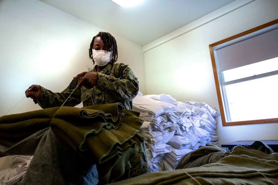 A service member wearing a face mask organizes supplies.