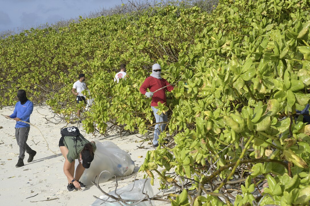 Sailors clean trash from a beach.