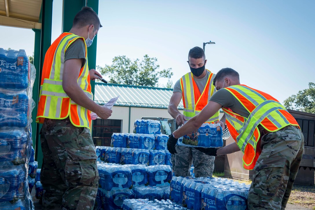 Airmen place cases of water on pallets.