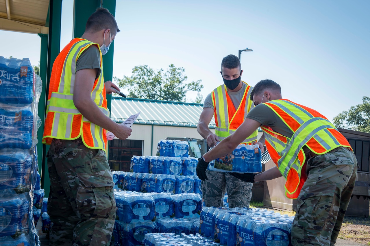 Airmen place cases of water on pallets.