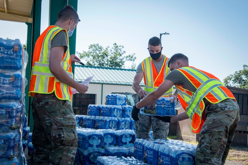 Airmen place cases of water on pallets.