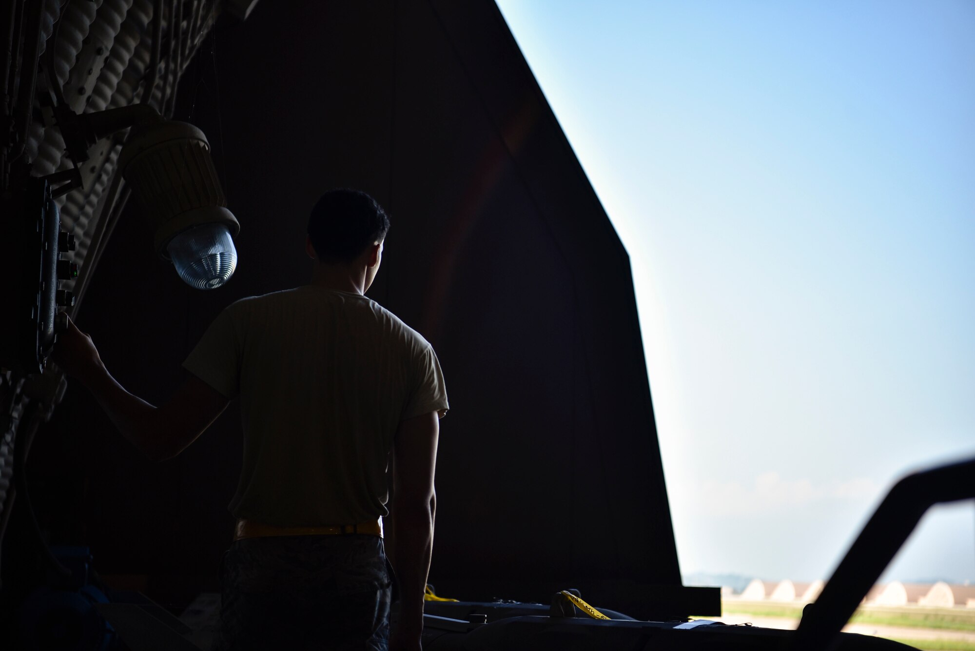 A photo of an Airman opening a hangar door.