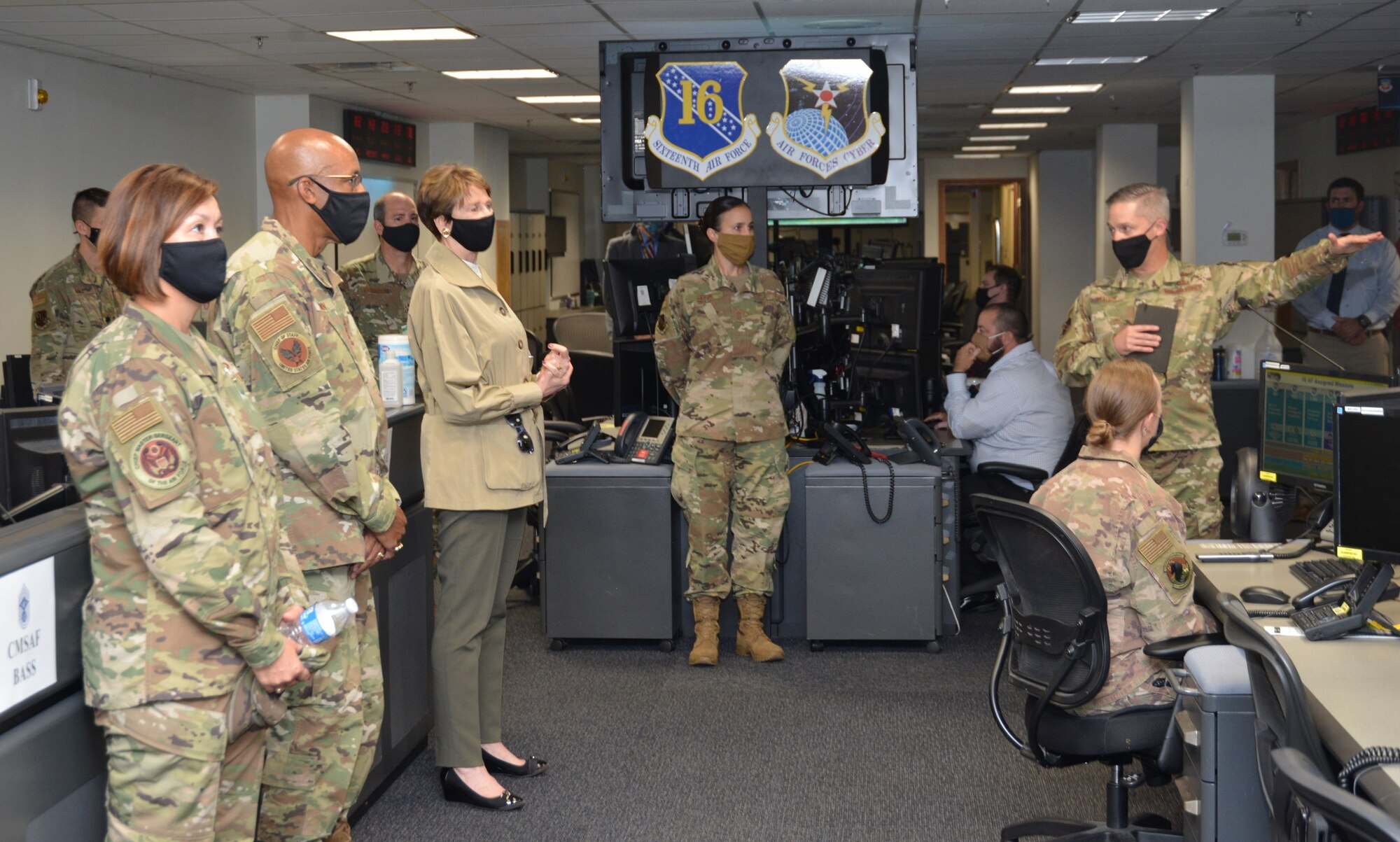 Civilian and military personnel in a meeting, standing.