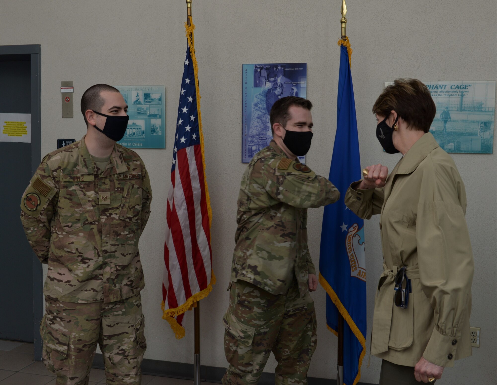 Two Airmen with one bumping elbows with the Secretary of the Air Force.