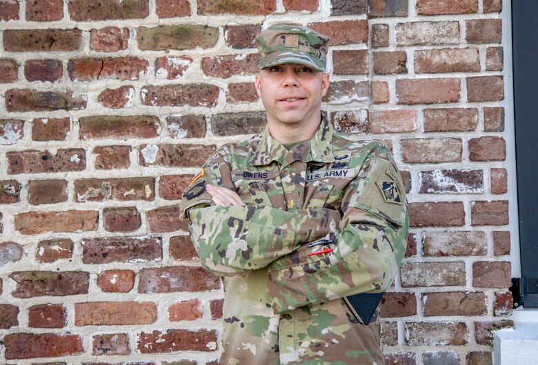 Man stands against a brick wall.