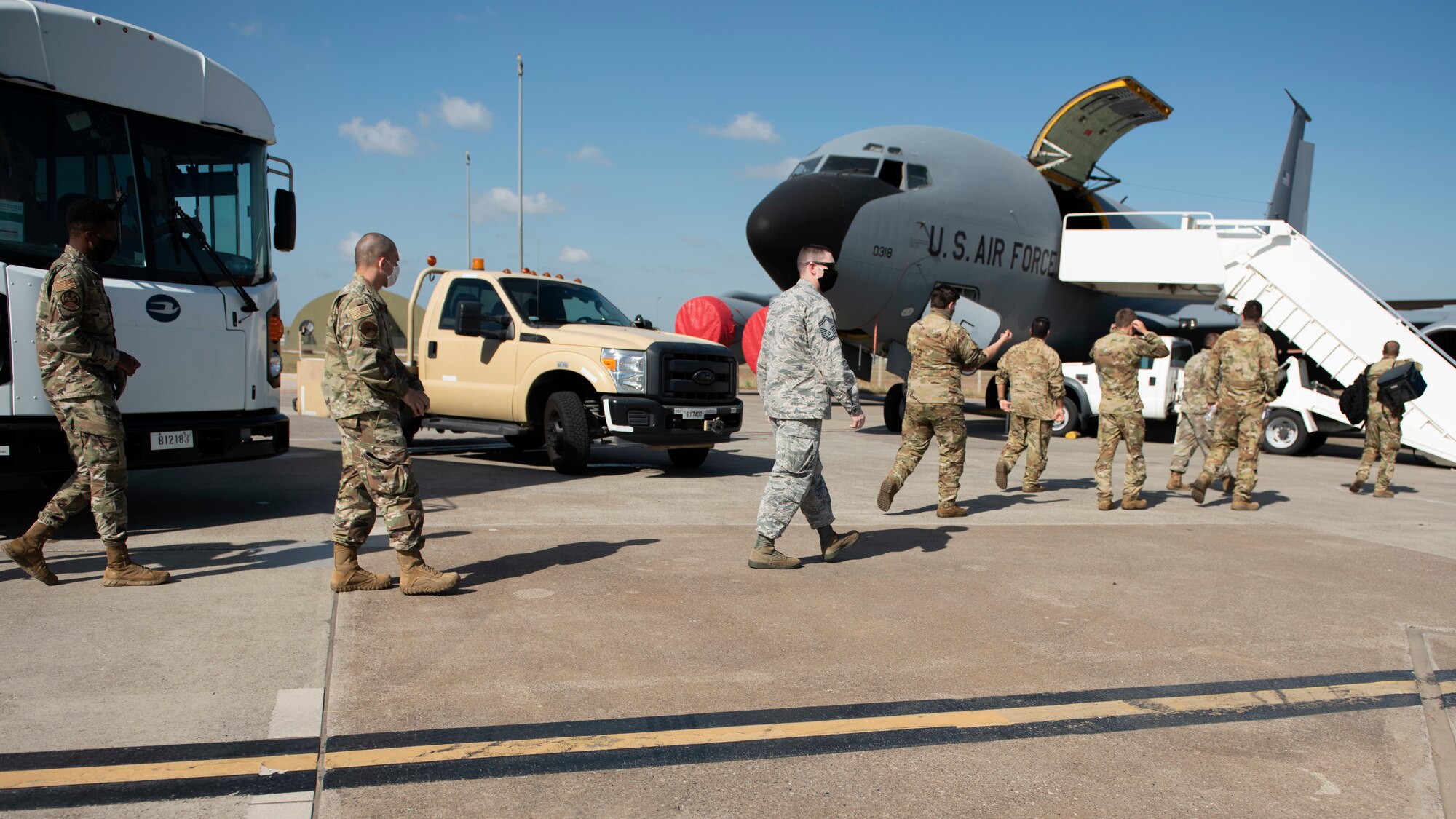 Several Airmen walk off of a bus and walk towards a KC-135 Stratotanker parked on the Incirlik Air Base flight line, August 17, 2020.