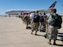 Airmen wait in line to board a jet for deployment