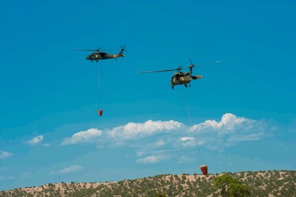 The Colorado National Guard is helping fight wildfires in the state in August 2020 with a CH-47 Chinook helicopter and two UH-60 Black Hawk helicopters, like these shown with aerial water buckets July 3, 2018, at Buckley Air Force Base, Aurora, Colorado.