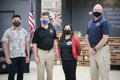 People pose in front of boxes of laptop computers.