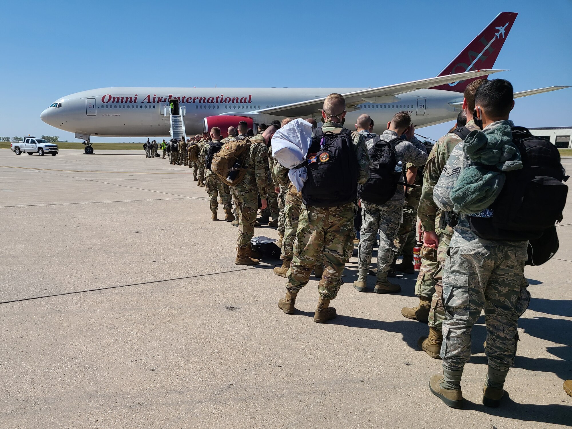 Airmen wait in line to board a jet for deployment