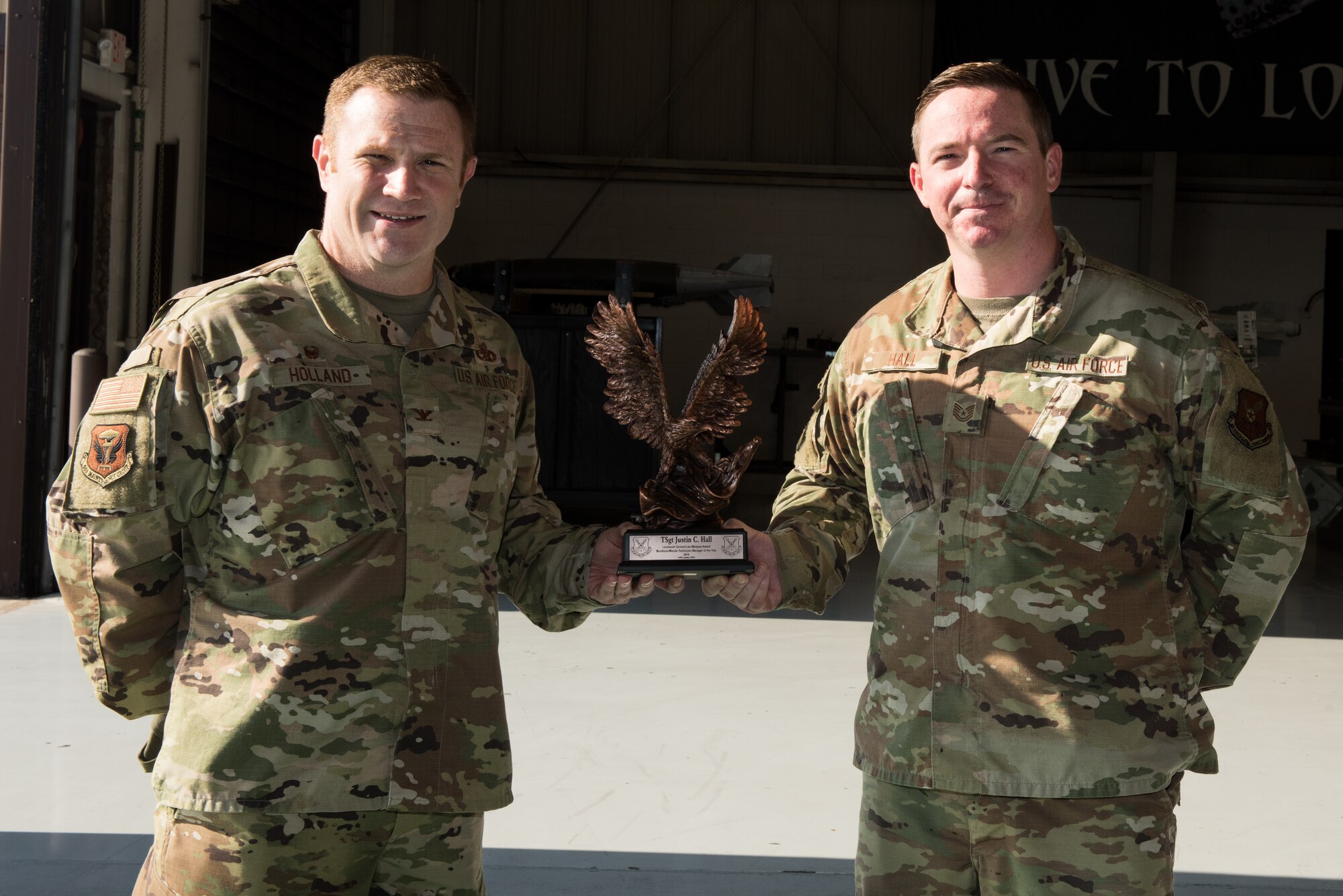 U.S. Air Force Col. Jeffrey Holland, 509th Maintenance Group commander, left, and Tech. Sgt. Justin Hall, 509th MXG loading standardization crew member, right, stands for photo with the Lt. Gen. Leo Marquez Award at Whiteman Air Force Base, Missouri, Aug. 14, 2020. Hall won the award of Technician Supervisor Category NCO Munitions/Missile Maintenance. This award recognizes military and civil service aircraft, munitions, and missile maintenance personnel who perform hands-on maintenance or manage a maintenance function. (U.S. Air Force photo by Airman 1st Class Christina Carter)