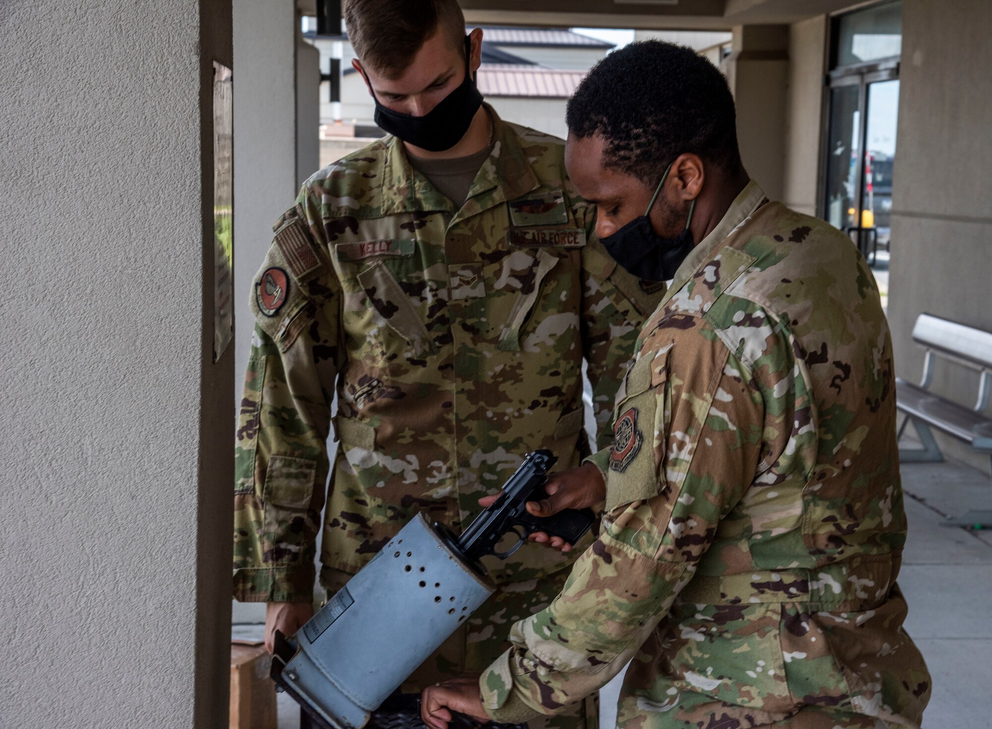 Airman 1st Class Kristopher Kelly, a 9th Airlift Squadron loadmaster (left) and Senior Airman Brayon Moore, a 9th Airlift Squadron loadmaster clear a weapon Aug. 20, 2020, at Dover Air Force Base, Delaware. Dover One Stop shop has a clearing barrel right outside their office to shorten the time required for flight crews to get their weapons. (U.S. Air Force Photo by Airman 1st Class Jonathan Harding)