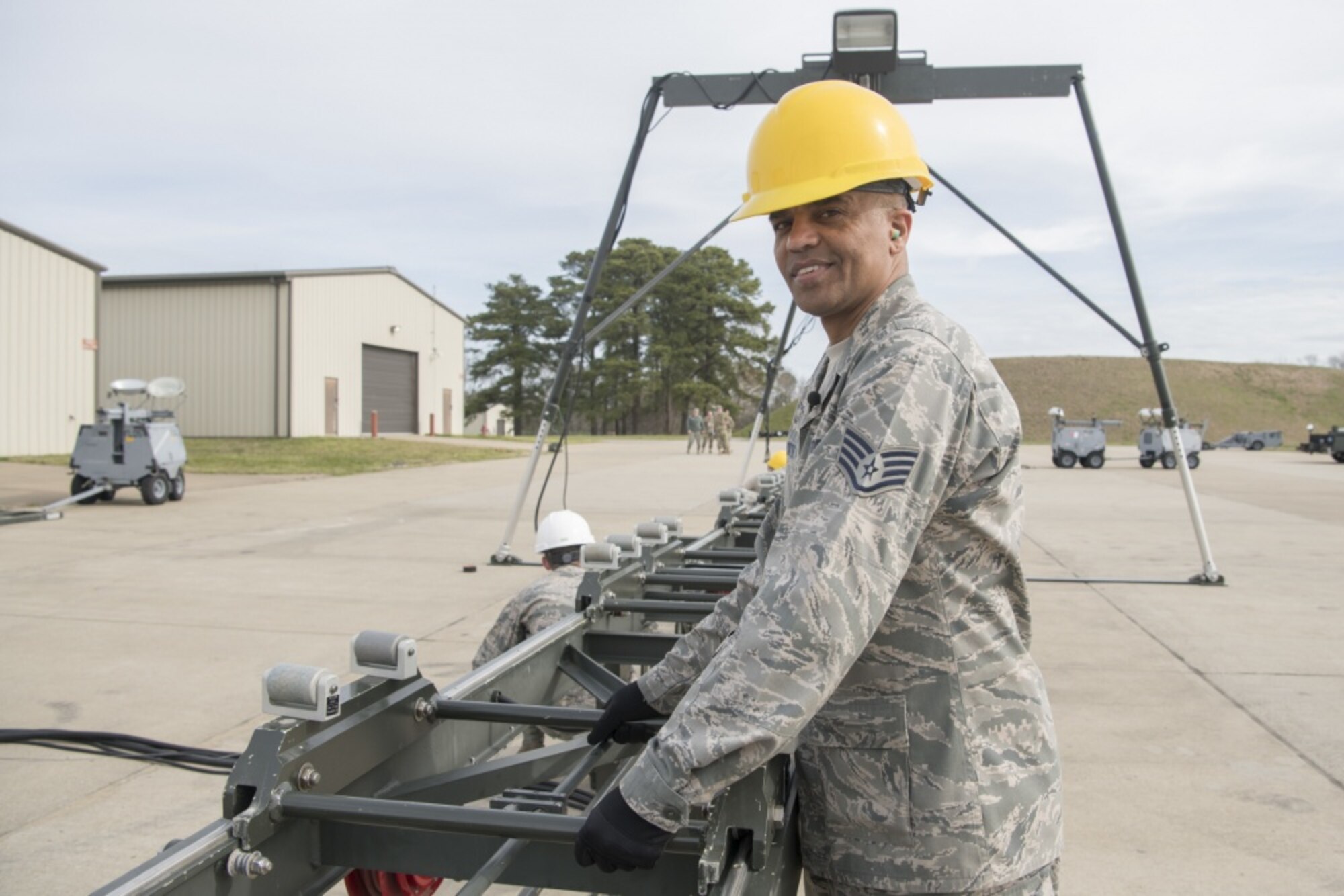 An Airman wearing a yellow hardhat is assembling a conveyer belt