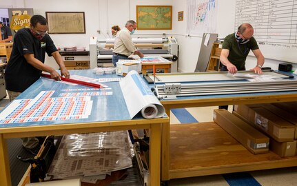 Employees assigned to Shop 71, Sign Shop, at Puget Sound Naval Shipyard & Intermediate Maintenance Facility work to produce signs as part of the shipyard's COVID-19 response and education efforts.