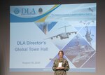 female Navy Vice Admiral stands in front of screen at DLA town hall.