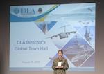 female Navy Vice Admiral stands in front of screen at DLA town hall.